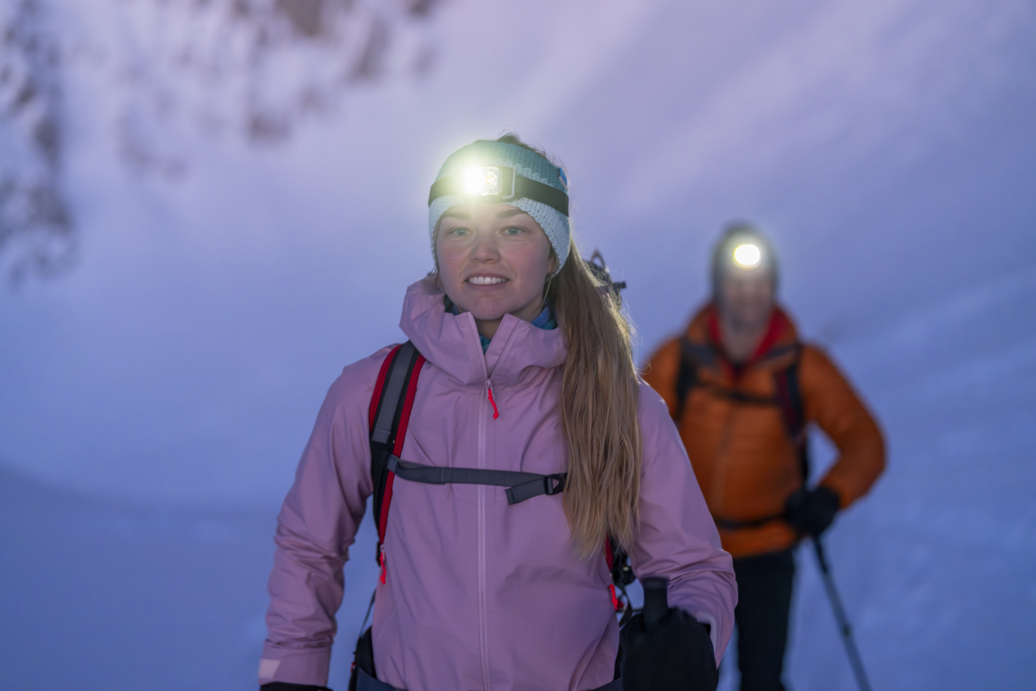 Young Couple Hiking in Snowy Mountains at Dawn with Headlamps